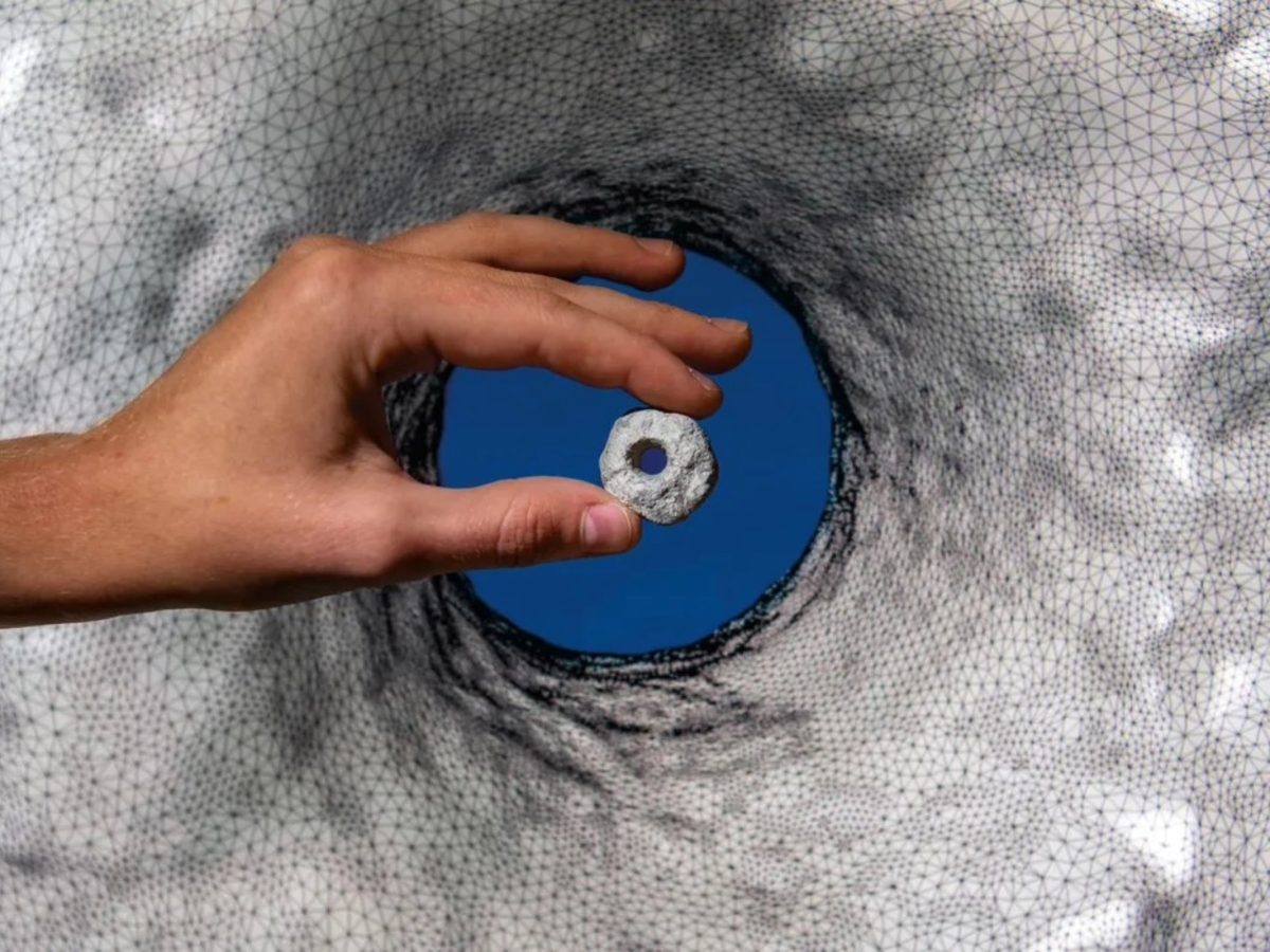 Pedra perfurada com 12 mil anos tendo como pano de fundo uma imagem do seu modelo 3D. Fotografia de Daniel Rolider/Smithsonian Magazine.