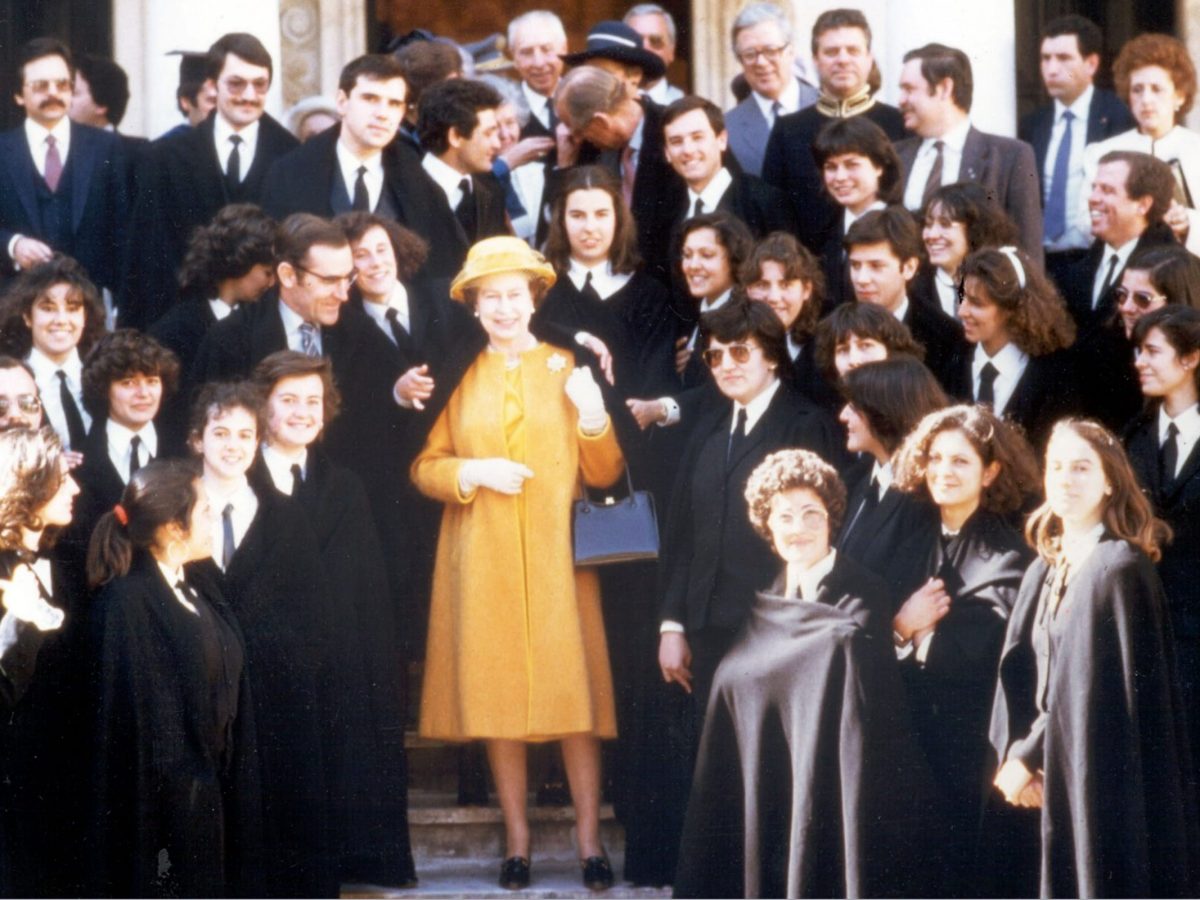 A rainha Isabel II ao centro, recebendo uma homenagem dos estudantes, que romperam com o protocolo real, com a capa académica, e o Presidente da República, António Ramalho Eanes, do seu lado direito, cercados por estudantes da academia de Évora.